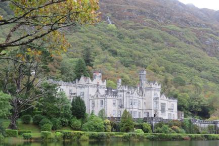 Irish castle along the lake. The white towers are reflected in the surface of the lake.